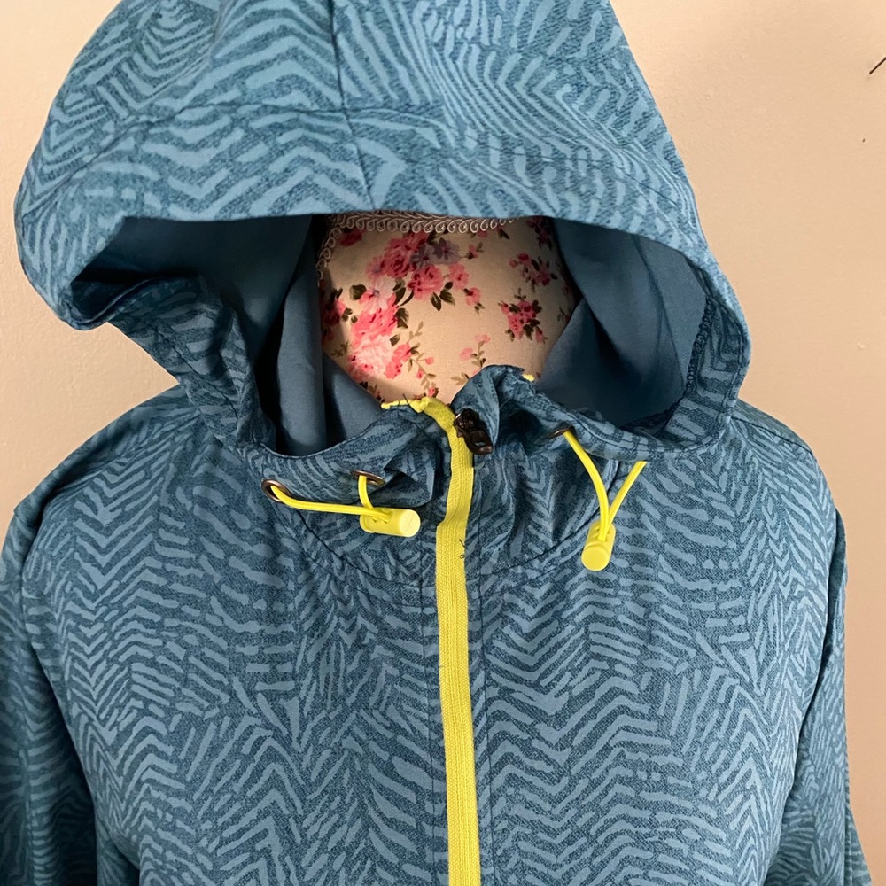 Turquoise patterned lightweight windbreaker with yellow zipper and pulls.